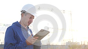 Electrical worker engineer a working with digital tablet, near tower with electricity. Business energy technology