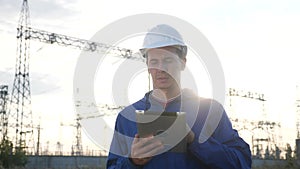 Electrical worker engineer a working with power digital tablet, near tower with electricity. Business energy technology