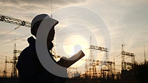 electrical worker silhouette engineer a working with digital tablet, near tower with electricity. energy business