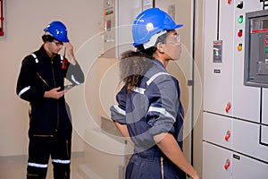 Electrical young asian woman and man engineer examining maintenance cabinet system electric in control room.