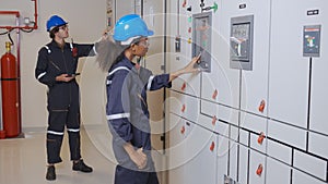 Electrical young asian woman and man engineer examining maintenance cabinet system electric in control room.