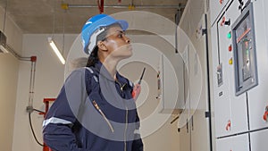 Electrical young woman engineer examining maintenance cabinet system electric in the control room.