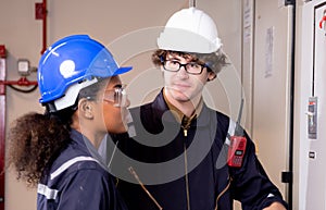Electrical young woman and man engineer examining maintenance cabinet system electric in the control room.