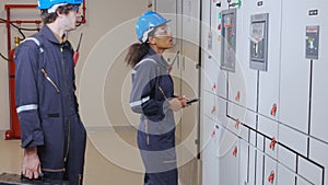 Electrical young woman and man engineer examining maintenance cabinet system electric in the control room.