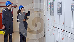 Electrical young woman and man engineer examining maintenance cabinet system electric in the control room.