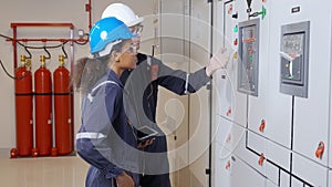 Electrical young woman and man engineer examining maintenance cabinet system electric in the control room.