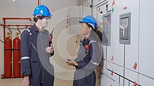 Electrical young woman and man engineer examining maintenance cabinet system electric in the control room.