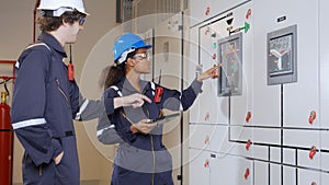 Electrical young woman and man engineer examining maintenance cabinet system electric in the control room.