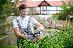 Electrically powered chain saw in hands of an experienced gardening worker