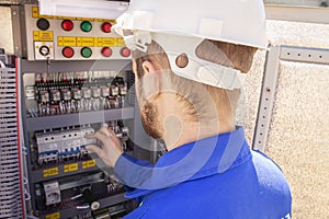 The electrician adjusts the electrical cabinet. engineer in helmet is testing electrical equipment