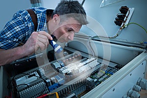 Electrician analyzing fusebox with torch