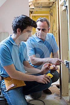 Electrician With Apprentice Working In New Home