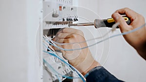 An electrician assembles an electrical panel in an apartment. Electrical box contains many terminals, relays, wires and