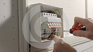 Electrician assembles electrical panel. Close up of a mans hands tightening a screw with a screwdriver and turning on