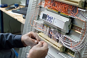 Hands of electrician assembling industrial HVAC control box in workshop. Close-up photo.