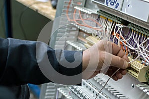 Electrician assembling industrial HVAC control panel in workshop. Close-up photo.