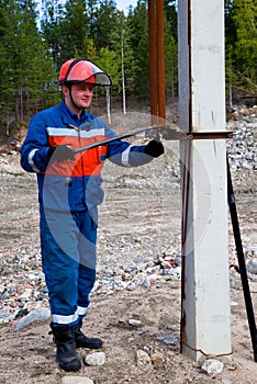 Electrician in blue overalls makes switching