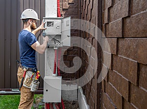 Electrician Builder at work, examines the cable connection in the electrical line in the fuselage of an industrial switchboard.