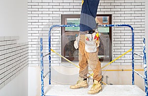 Electrician Builder at work, installation of lamps at height. Professional in overalls with an electrical tool. On the background