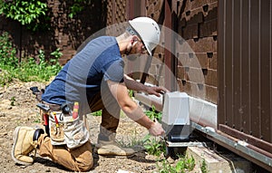 Electrician Builder at work, servicing the fuselage industrial switchboard. Professional in overalls with an electrician`s tool