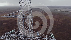 Electrician on carcass of power transmission tower on ground