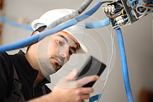 Electrician checking phone installing electrical system