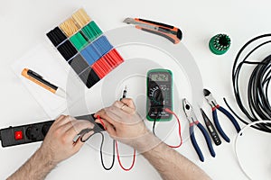 Electrician checking socket voltage with digital multimeter