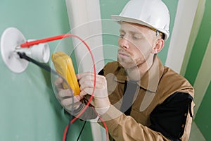 electrician checking socket voltage with digital multimeter