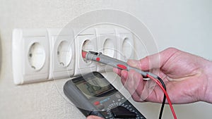 Electrician checking socket voltage with multimeter