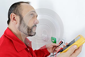 electrician checking socket voltage using multimeter