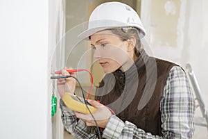electrician checking socket voltage using multimeter