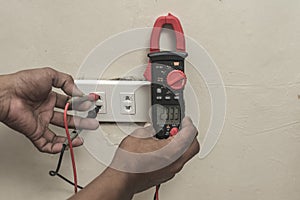 An electrician checking the voltage of a newly installed outlet in the living room with an ammeter tester