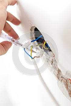 Electrician checking the wiring in a wall socket