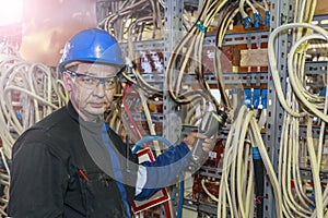 An electrician checks with a thermal imager the temperature of the power cable in an energy installer