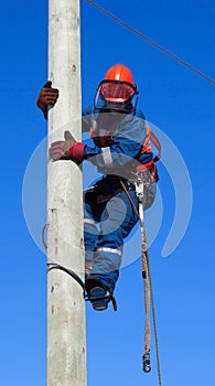 Electrician climbs the pole transmission line