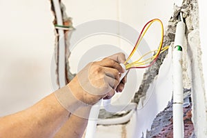 Electrician concealing electicity power wire lines within plastic tube embeded into wall