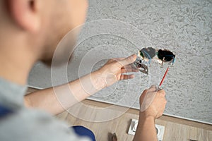 electrician connects the sockets to the electrical wires on the wall, work on installing outlets.