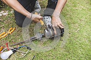 An electrician dismantles a garden light with a pair of pliers. Electrical repair service at the garden of a house