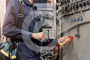 Electrician engineer checks electrical circuit in control panel for high current and voltage, starting and commissioning