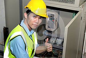 Electrician engineer gave a thumbs up at the control room of plant. Wearing safety vest and yellow helmet