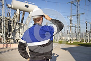 Electrician engineer on power electric station look at industrial equipment. Technician in helmet on electro substation photo