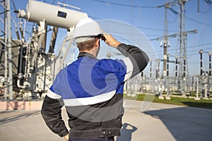 Electrician engineer on power electric station look at industrial equipment. Technician in helmet on electro substation
