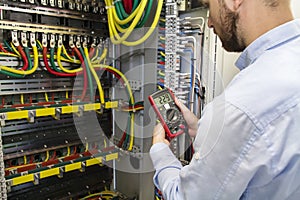 Electrician engineer testing cabling connection of high voltage power electric line in industrial distribution fuse board photo