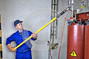 Electrician engineer uses discharge stick to earth grounding transformer.