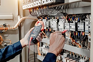 Electrician engineer uses a multimeter to test the electrical installation and power line current in an electrical system control