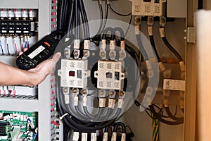 Electrician engineer work tester measuring voltage and current of power electric line in electical cabinet control