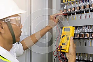 Electrician engineer work tester measuring voltage and current of power electric line in electical cabinet control