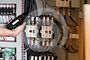 Electrician engineer work tester measuring voltage and current of power electric line in electical cabinet control