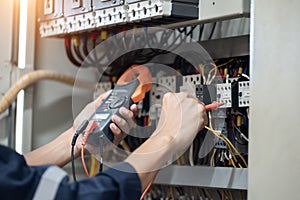 Electrician engineer work tester measuring voltage and current of power electric line in electrical cabinet control , concept chec