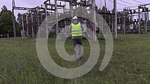 Electrician engineer writing documentation and walking in substation
